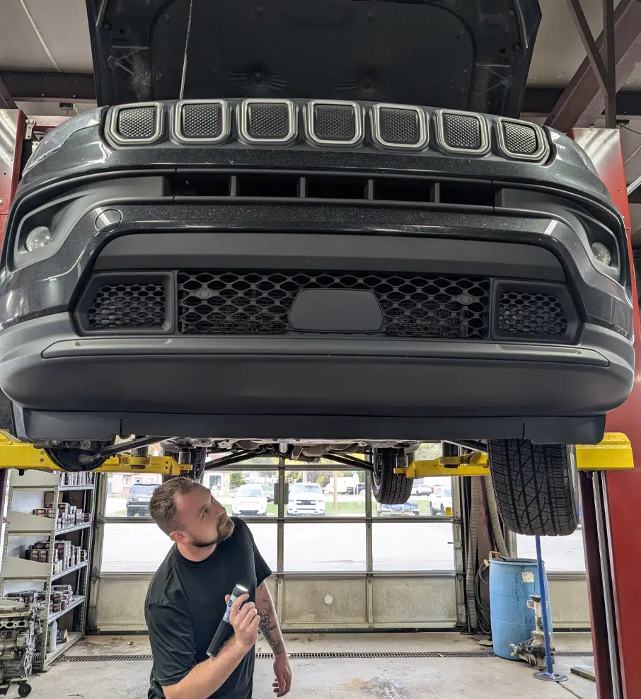 Mechanic working on lifted vehicle.