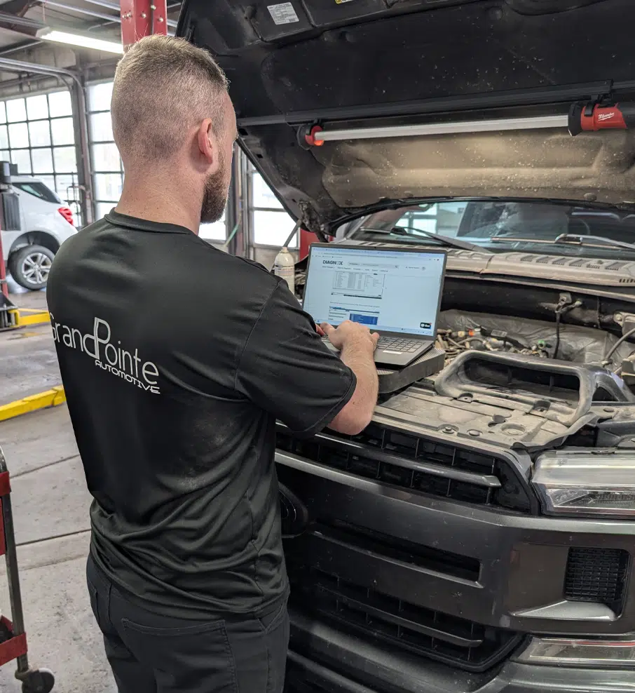 Auto Diagnostics In Grand Blanc Township, MI At Grand Pointe Automotive. Mechanic diagnosing vehicle with laptop