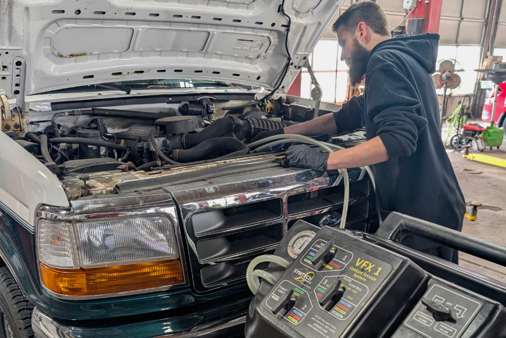 Grand Pointe Automotive Launches Comprehensive Thermal Management Inspections for Summer Travel. Image of a technician using a radiator coolant exchanger on a truck