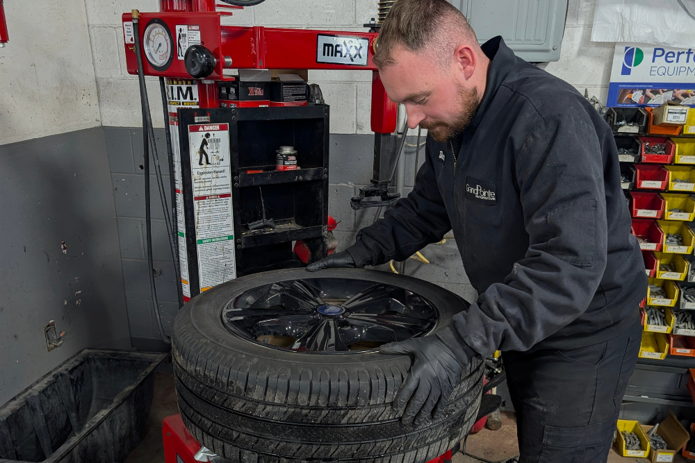 Tire Shop & Precision Alignments in Grand Blanc, MI At Grand Pointe Automotive. Image of Auto technician mounting a tire for premium tire and precision alignment service